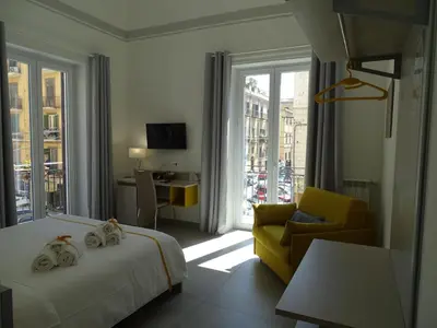 a hotel room with two beds and a yellow chair at Le Quattro Stagioni - Rooms & Suites in Palermo