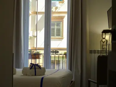 a bedroom with a bed and a large window at Le Quattro Stagioni - Rooms & Suites in Palermo