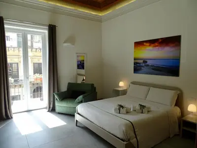 a bedroom with a bed and a chair and a window at Le Quattro Stagioni - Rooms & Suites in Palermo