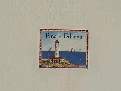 a sign hanging on a wall with a lighthouse at HOME HOLIDAY PINO&FABIANA in San Vito lo Capo