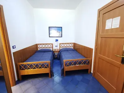 two beds in a room with a door at Al Baglio in Mondello