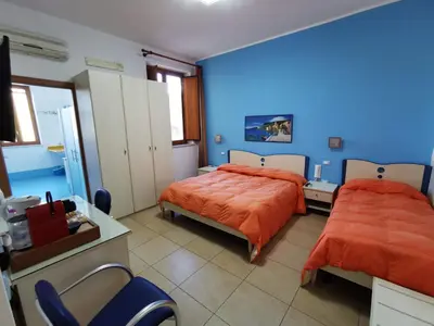 a bedroom with two beds and a blue wall at Al Baglio in Mondello