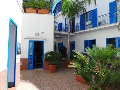 a building with blue doors and plants in a courtyard at Al Baglio in Mondello