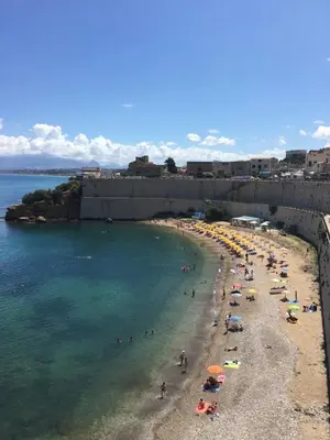 a beach with a bunch of people in the water at Alice's Apartment in Castellammare del Golfo