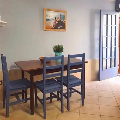 a dining room table with blue chairs and a painting on the wall at Alice's Apartment in Castellammare del Golfo
