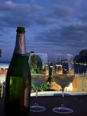 a bottle of wine and two glasses on a table at Ashur apartments in Mondello