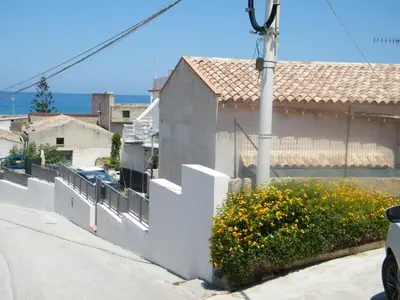 a house with a white fence and some flowers at Casa Rachele ad Alcamo Marina in Alcamo Marina