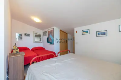 a bedroom with a bed and a red couch at Villa Limuti con piscina condominiale in Campofelice di Roccella