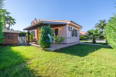 a house with a green yard in front of it at Villa Limuti con piscina condominiale in Campofelice di Roccella