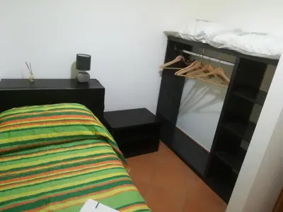 a bedroom with a bed and a black cabinet with hangers at Villa Mimmo in Lascari