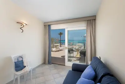 a bedroom with two beds and a blue couch at Hotel Riviera in San Vito lo Capo