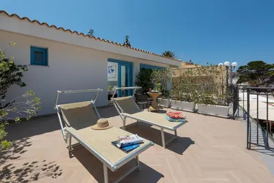 a bedroom with a bed with blue pillows on it at Hotel Riviera in San Vito lo Capo