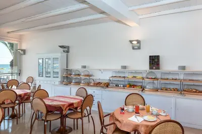 a restaurant with tables and chairs with food on them at Hotel Riviera in San Vito lo Capo