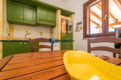 a kitchen with a wooden table and green cabinets at Villa Nettuno con piscina privata in Campofelice di Roccella