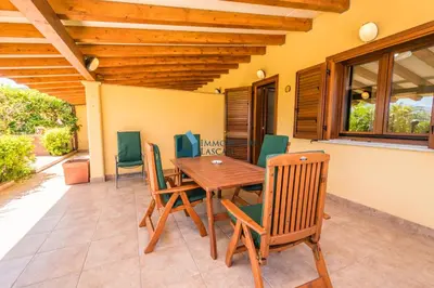 a wooden table and chairs on a patio at Villa Nettuno con piscina privata in Campofelice di Roccella