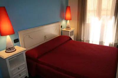 a bedroom with a red bed with two lamps at Locanda Re Ruggero in Monreale