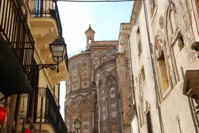 an old building with a clock tower in a street at Locanda Re Ruggero in Monreale