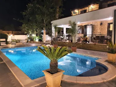 a swimming pool at night with a palm tree in a pot at 25min da Cefalù e Palermo Piscina pvt, 4camere, 150m dal mare in Trabia