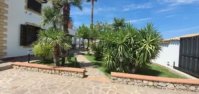 a walkway with benches and palm trees next to a building at 25min da Cefalù e Palermo Piscina pvt, 4camere, 150m dal mare in Trabia
