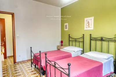 two beds in a room with green walls at Casa dei Coralli Panoramic Sea View Centro Storico By Sicily Home Solutions in Castellammare del Golfo