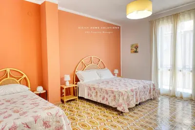 a bedroom with two beds and orange walls at Casa dei Coralli Panoramic Sea View Centro Storico By Sicily Home Solutions in Castellammare del Golfo