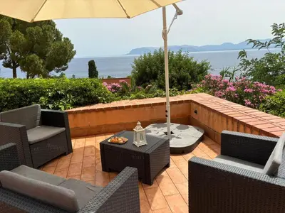 a patio with a table and chairs and an umbrella at Villa Hibiscus Scopello in Scopello
