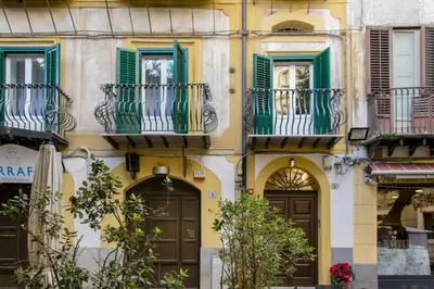 a building with green shutters and brown doors at Kala Rooms in Palermo