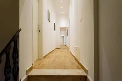 a hallway with white walls and a wooden floor at Kala Rooms in Palermo