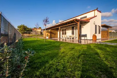 a house with a green lawn in front of it at Villa Barbara...a 100 passi dal mare!!!! in Lascari