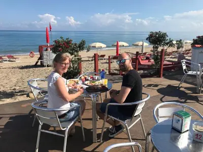 a man and woman sitting at a table on the beach at Villa Barbara...a 100 passi dal mare!!!! in Lascari