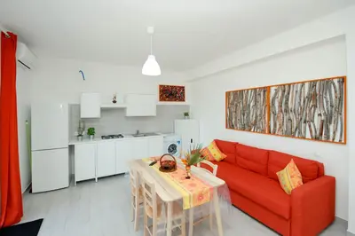 a living room with a red couch and a table at Villa Barbara...a 100 passi dal mare!!!! in Lascari