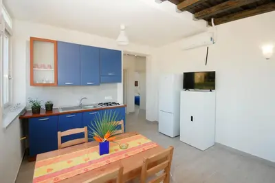 a kitchen with blue cabinets and a table and a refrigerator at Villa Pasquale...immersa nella tranquillita' in Lascari