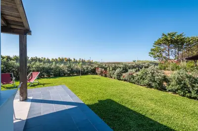 a garden with a patio and grass and flowers at Villa Pasquale...immersa nella tranquillita' in Lascari