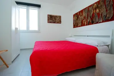 a red bed in a white room with a window at Villa Pasquale...immersa nella tranquillita' in Lascari