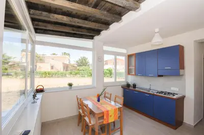 a kitchen with blue cabinets and a table with chairs at Villa Pasquale...immersa nella tranquillita' in Lascari