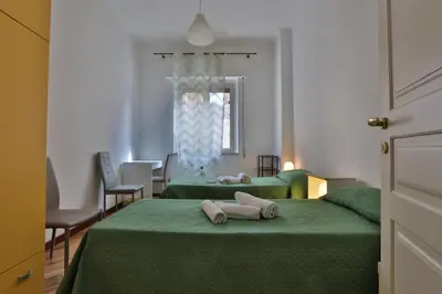 a room with two green beds and a window at Ai Bastioni del Massimo in Palermo