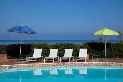 a group of chairs and umbrellas next to a pool at Riva Sea Apartments in Castellammare del Golfo