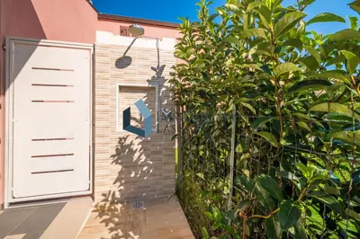 a building with a white door next to a bush at Villa Ricky, a pochi passi dal mare in Lascari