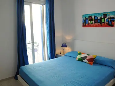 a bedroom with a blue bed with a window at Appartamento Irma Dario in San Vito lo Capo