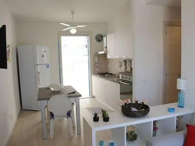 a kitchen with a table and a white refrigerator at Appartamento Irma Dario in San Vito lo Capo