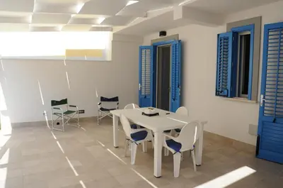 a dining room with a white table and chairs at Appartamento Irma Dario in San Vito lo Capo