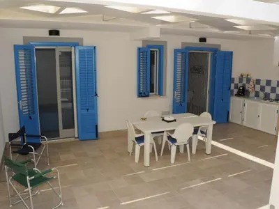 a dining room with blue doors and a table and chairs at Appartamento Irma Dario in San Vito lo Capo