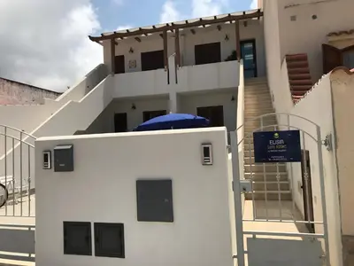 a white building with a blue umbrella on top of it at Elisir Suite Rooms by Marino Tourist in San Vito lo Capo