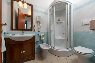 a bathroom with a sink and a toilet and a shower at Helios Hotel in San Vito lo Capo