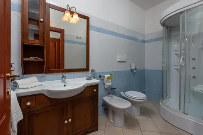 a bathroom with a sink and a toilet and a mirror at Helios Hotel in San Vito lo Capo