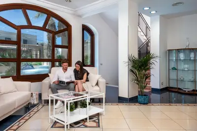 a man and woman sitting on a couch in a living room at Helios Hotel in San Vito lo Capo