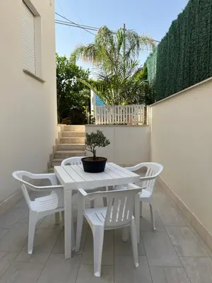 a white table and chairs with a potted plant on a patio at Villetta Azzurra in Alcamo Marina