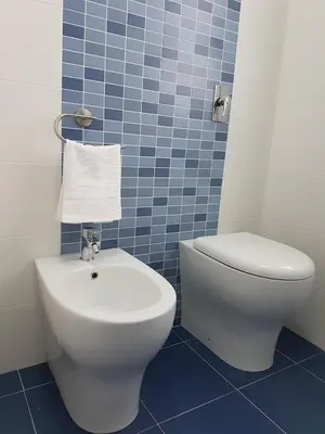 a blue tiled bathroom with a toilet and a sink at Villetta Azzurra in Alcamo Marina
