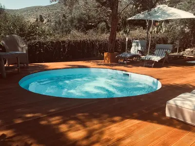 a pool on a wooden deck with chairs and an umbrella at Villa Rosemada, Mondello in Palermo