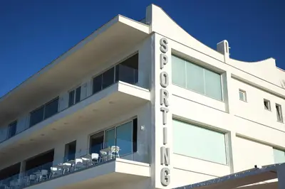 a white building with chairs on the balcony at Hotel Sporting Club in Altavilla Milicia
